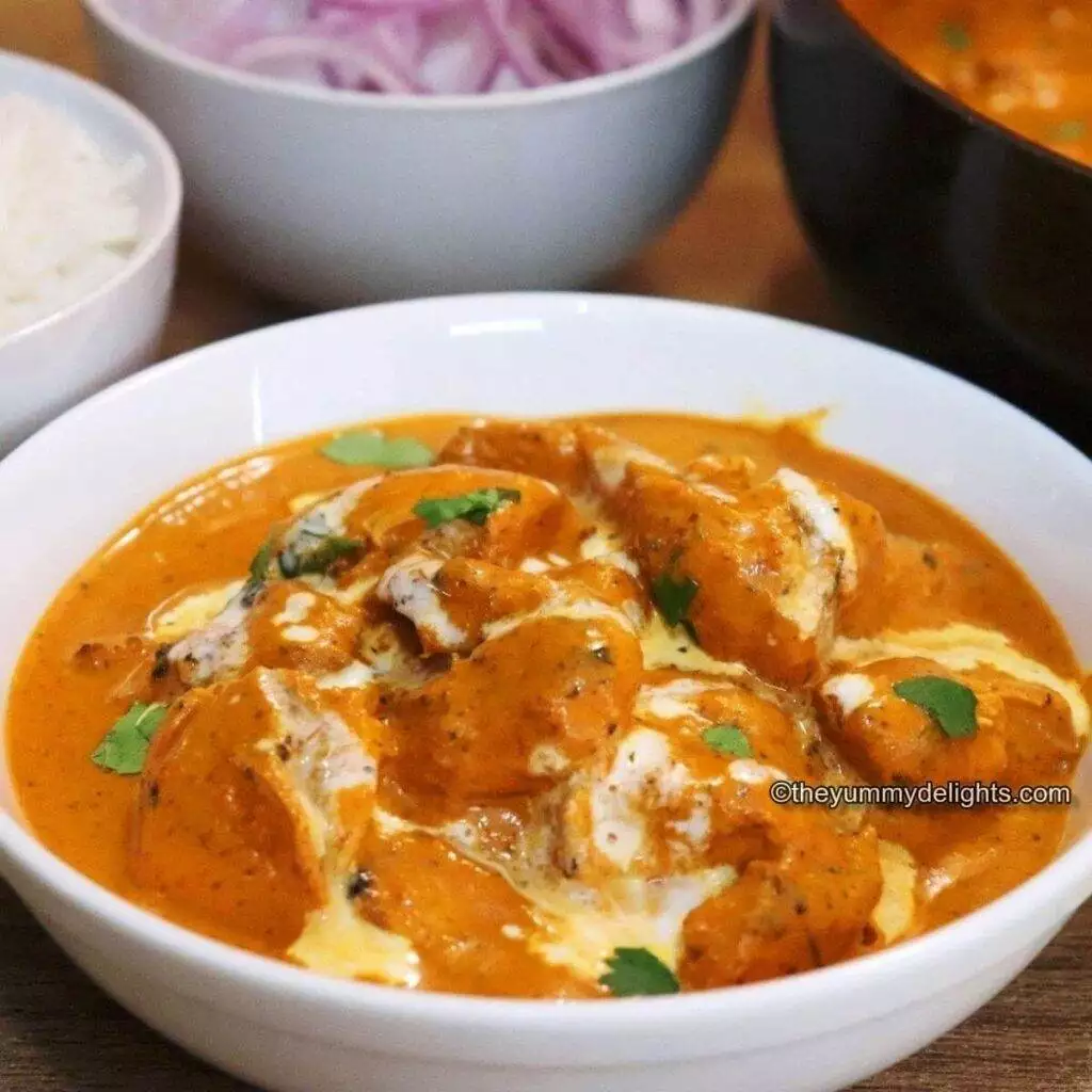 close-up of Indian butter chicken served in a white bowl.