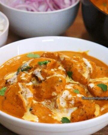 close-up of Indian butter chicken recipe served in a white bowl.