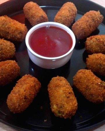 potato nuggets served on a black platter with tomato sauce.