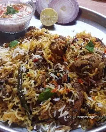 Hyderabadi biryani served with raita and onion slices.