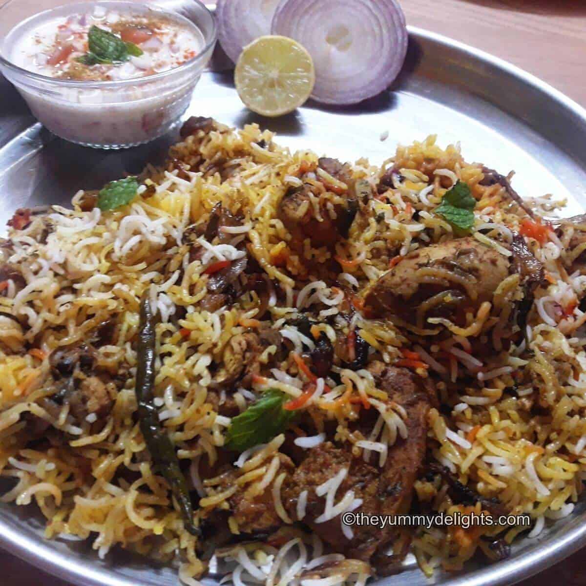 Hyderabadi biryani served with raita and onion slices.
