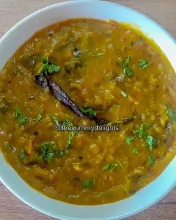 dal fry served in white bowl.