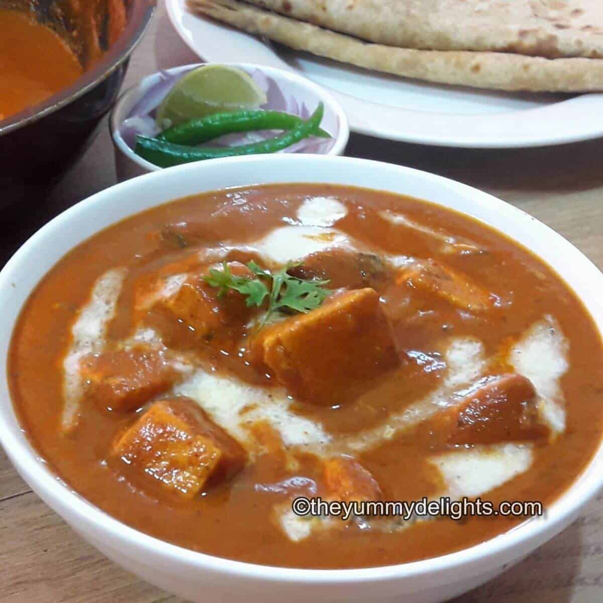 close up of paneer butter masala served with Roti & salad.