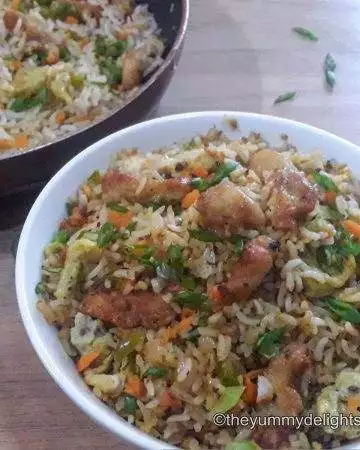 Chinese chicken fried rice served in a white bowl. Garnished with some spring onion greens.