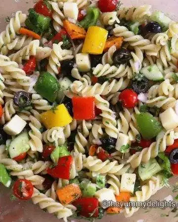pasta salad with colorful vegetables in a mixing bowl.