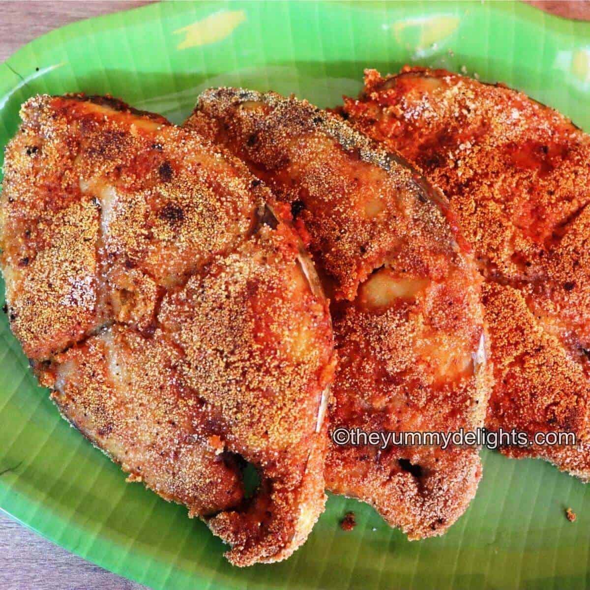 Manglorean rava fish fry served on a green colored plate.