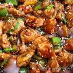 black pepper chicken stir-fry close-up image. Garnished with spring onion greens.