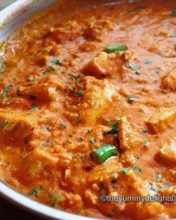 Garlic chicken curry in a pan. This garlic chicken curry is garnished with coriander leaves.