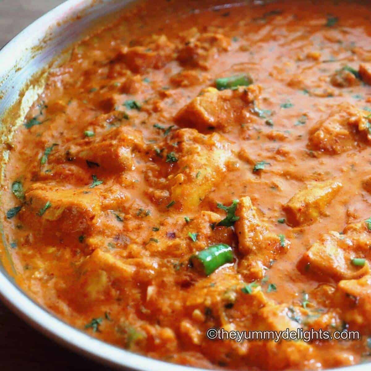 Garlic chicken curry in a pan. This garlic chicken curry is garnished with coriander leaves.