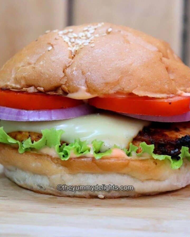 grilled cajun chicken sandwich placed on a chopping board. Side-view of the image.
