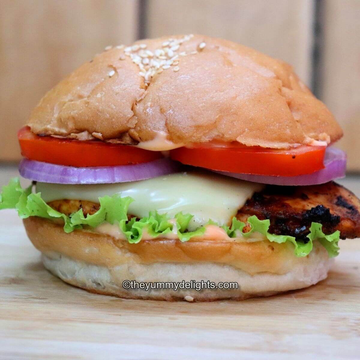 grilled cajun chicken sandwich placed on a chopping board. Side-view of the image.