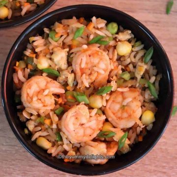top-view of prawn-fried rice in a black colored bowl.