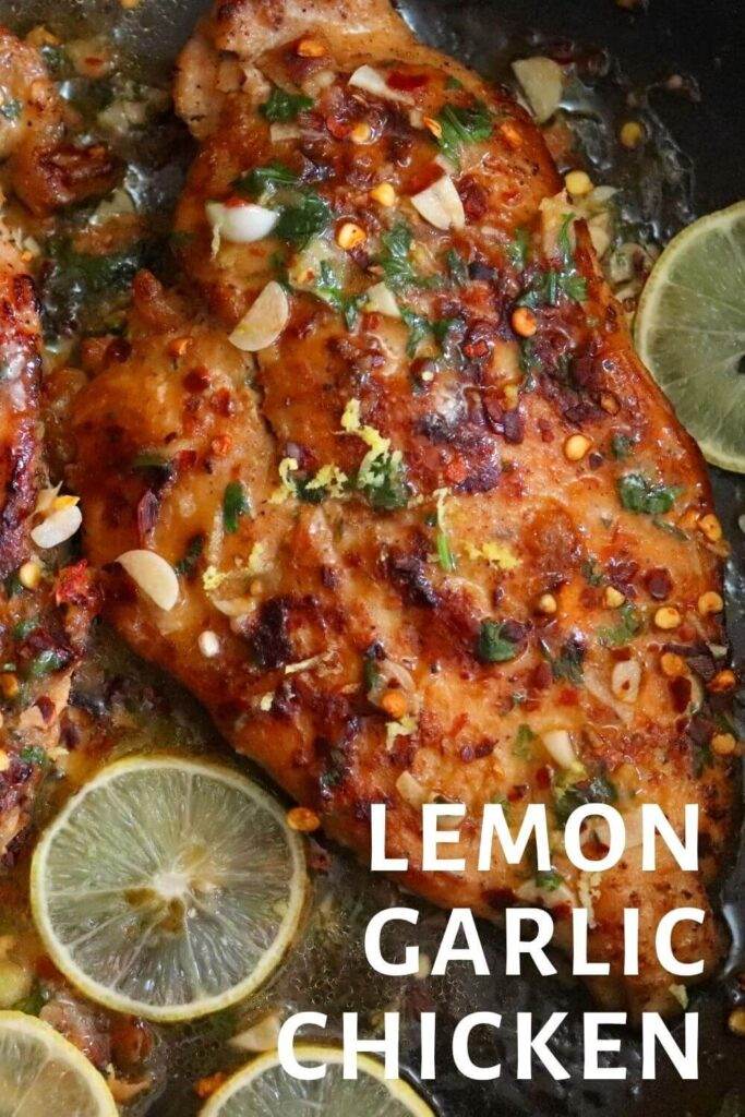 close up image of lemon garlic chicken breast in a pan garnished with lemon slices.