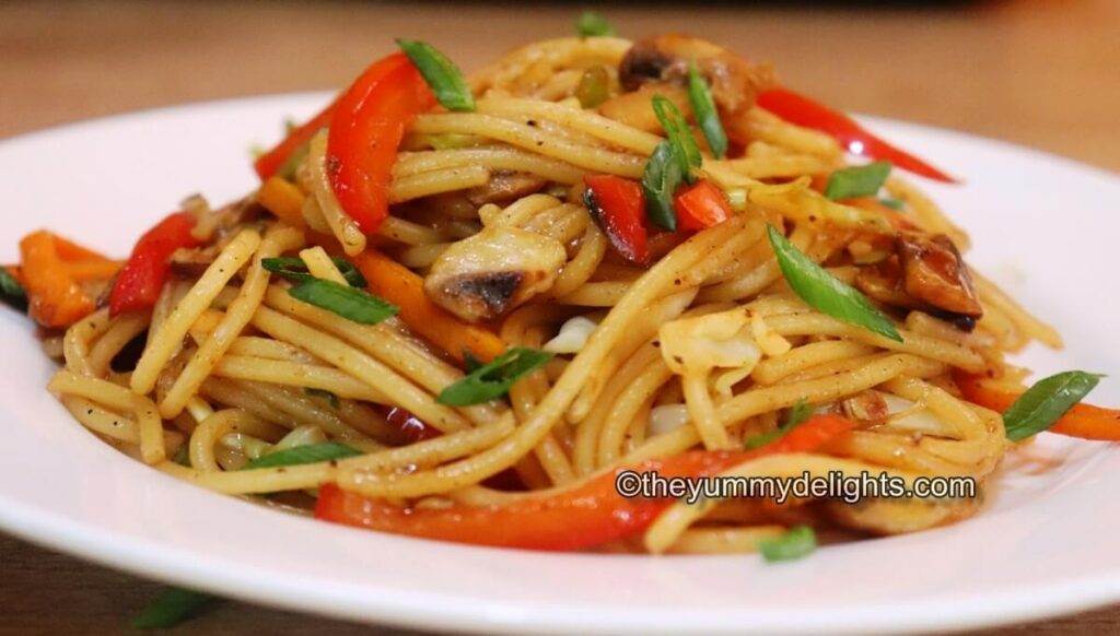 side view of veggie lo mein served on a white plate.