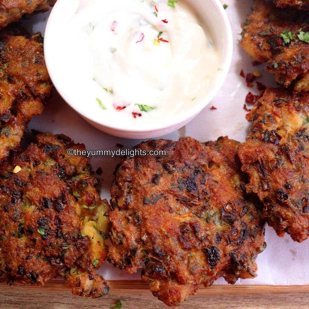 cheesy chicken fritters placed on a white plate. Served with Mayonnaise dip in a small bowl.