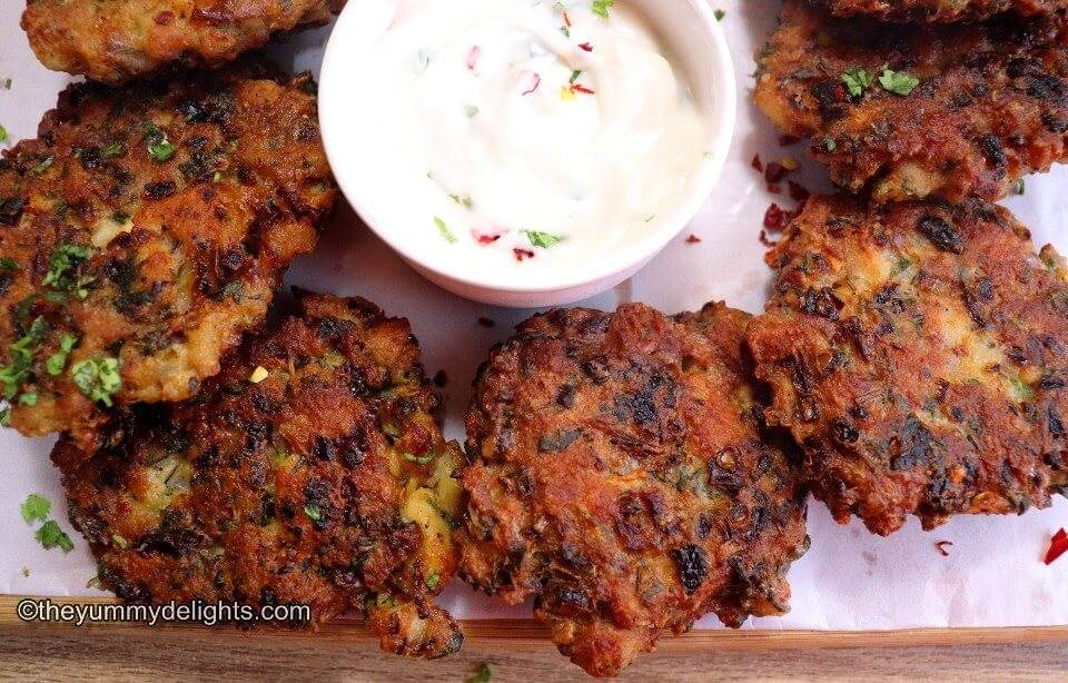 top view of chicken fritters placed on a plate next to each other. They are served with garlic -mayo dip.