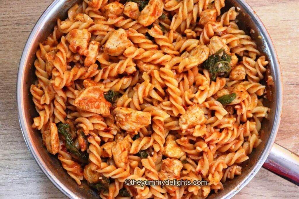 top videw of tomato spinach chicken pasta dish in the skillet.
