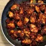 close-up of chicken masala fry in a black colored pan.