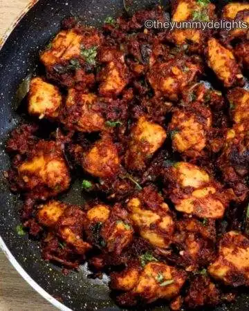 close-up of chicken masala fry in a black skillet.