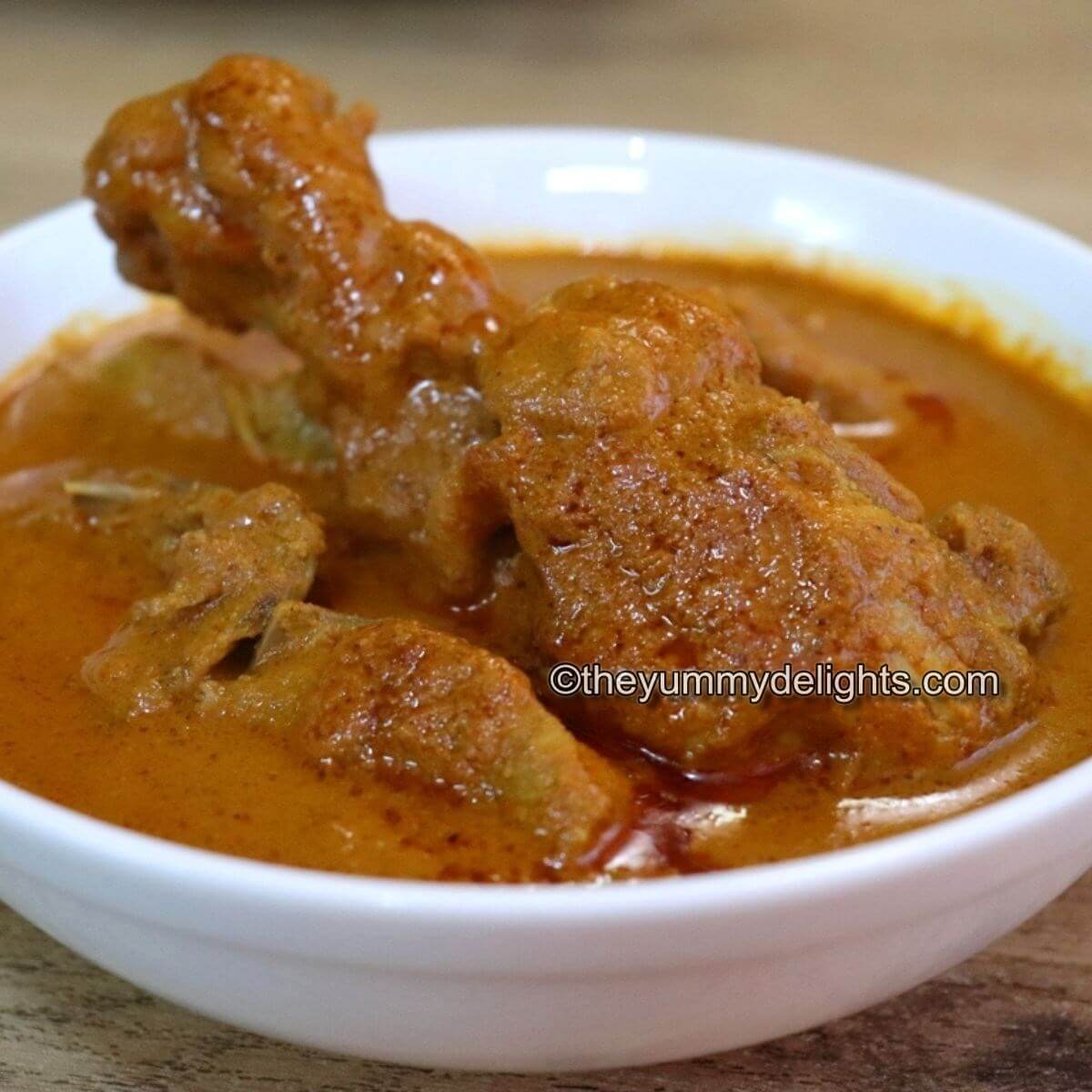 close-up of chicken xacuti curry served in white bowl.