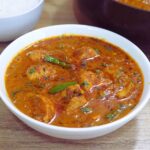 close-up of chicken handi served in a white bowl.