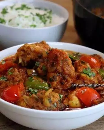 close-up of tomato chicken curry served in a white bowl.