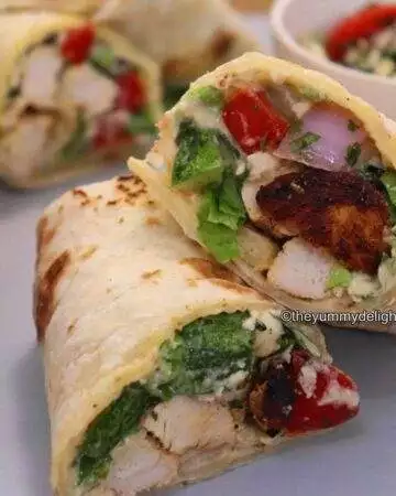 close-up of mediterranean chicken wrap, sliced in half and stacked.