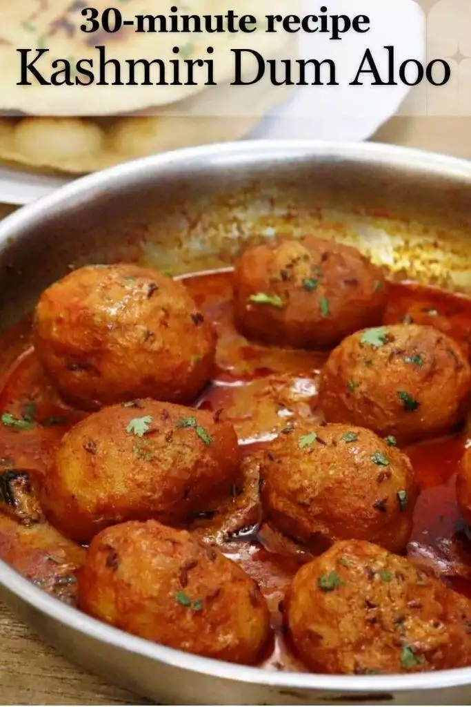 close-up of kashmiri dum aloo in a skillet, garnished with coriander leaves.