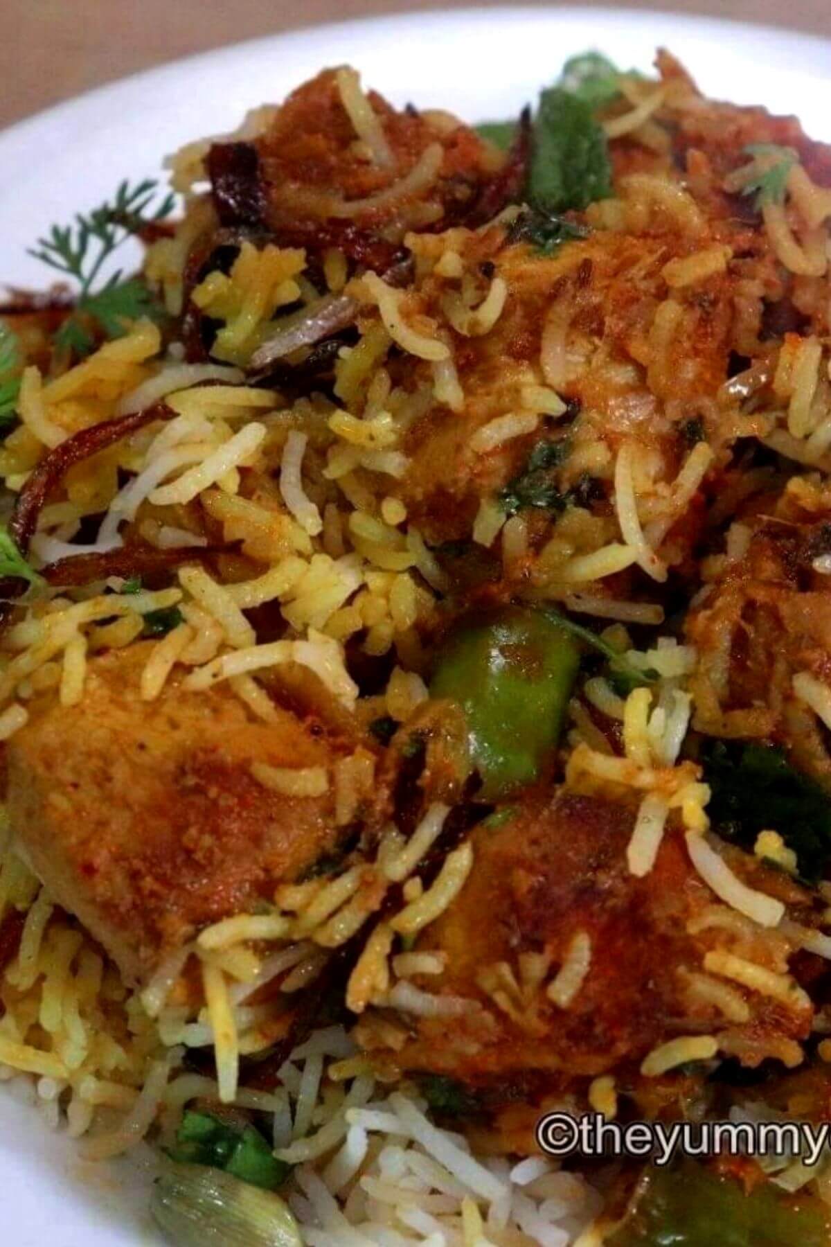 close-up of chicken tikka biryani in a white colored plate.