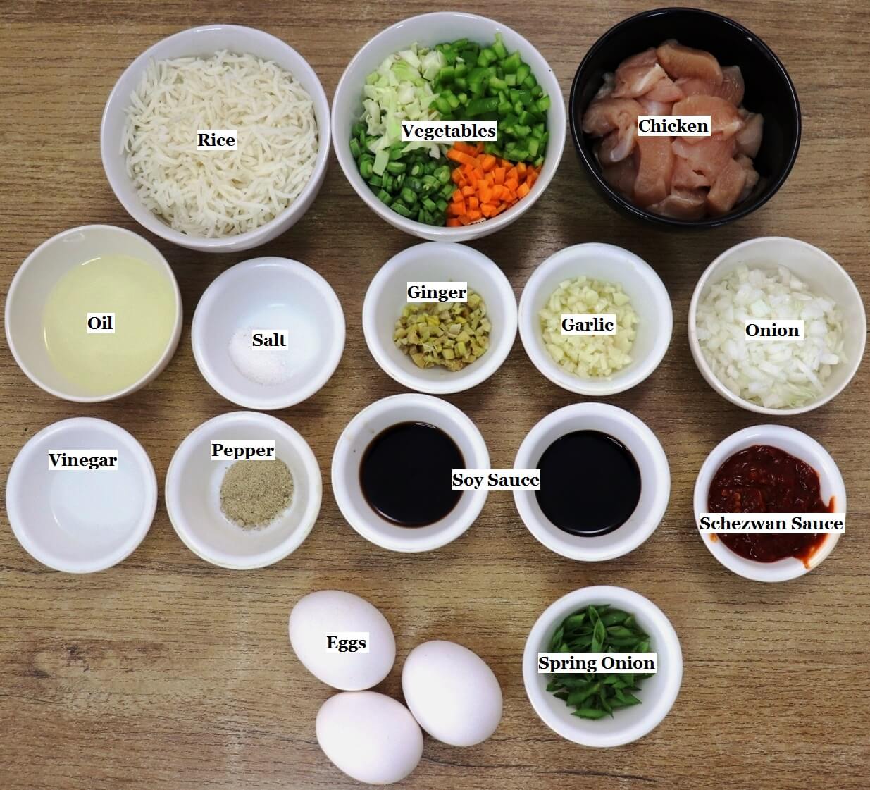 individually labeled ingredients to make schezwan chicken fried rice are laid out on a table.