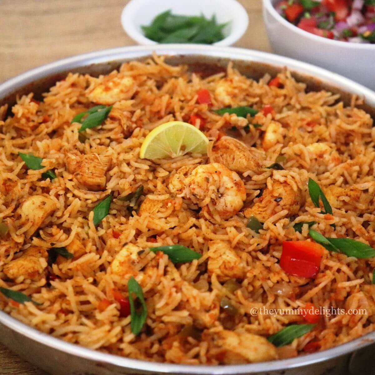 close-up of chicken jambalaya recipe. Garnished with lemon wedge and spring onion greens. Serve with a salad on the side.