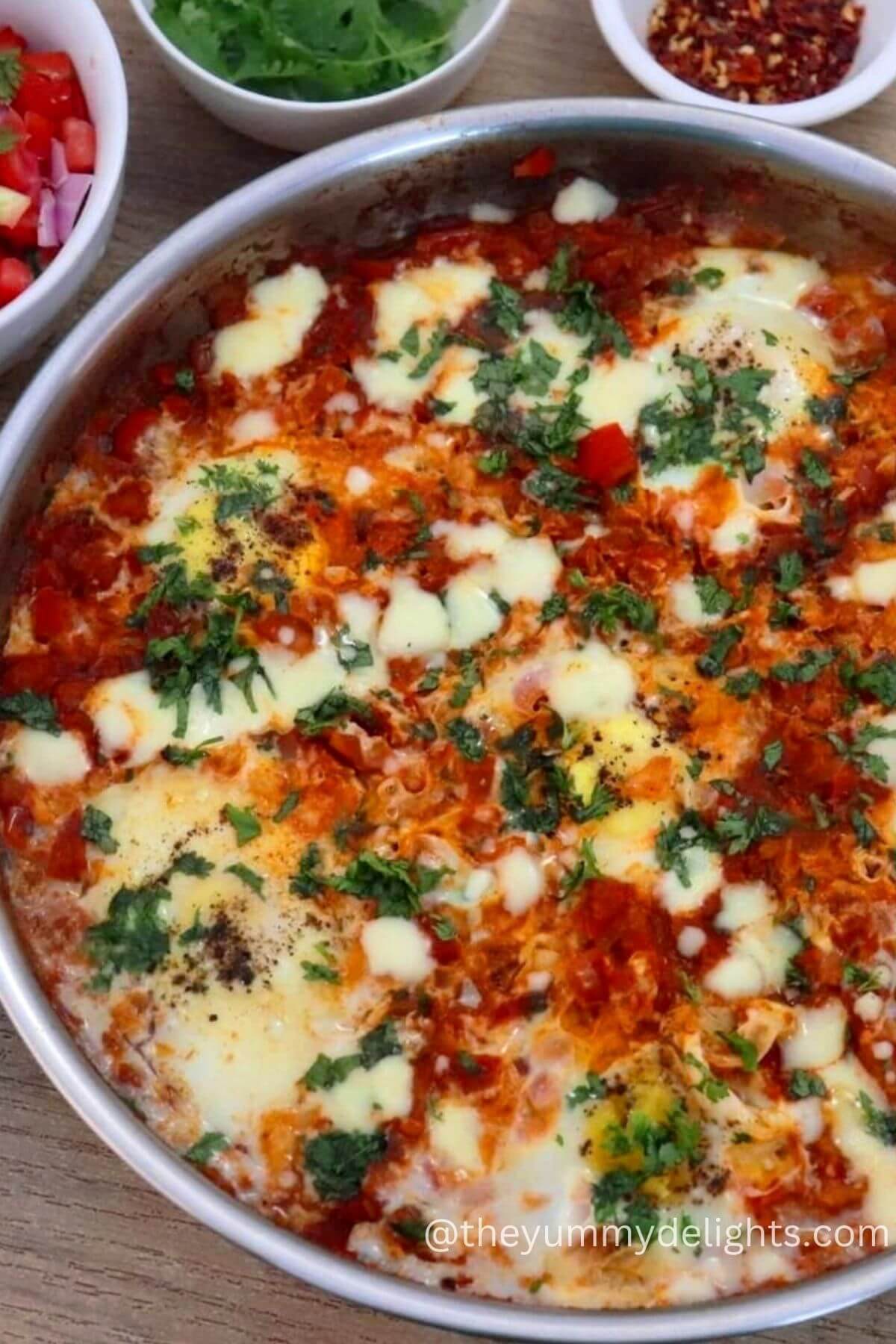 top view of shakshuka in a skillet. Garnished with feta cheese and cilantro.