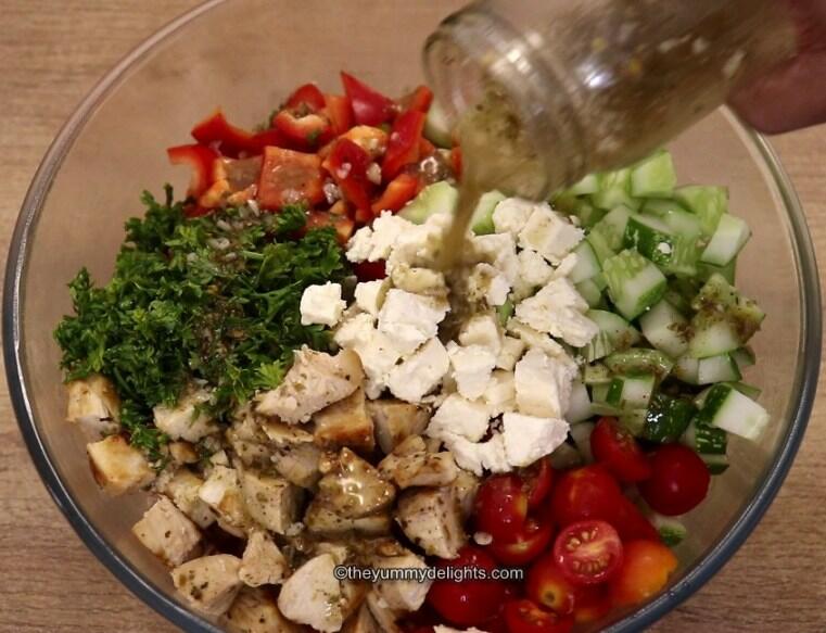 adding greek dressing to the salad.