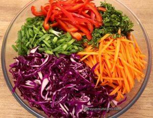 asian slaw vegetables and herbs in a mixing bowl.