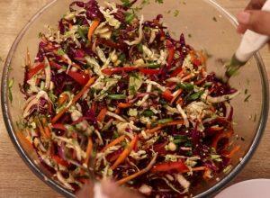 tossing the asian slaw after the adiition of peanuts and sesame seeds.