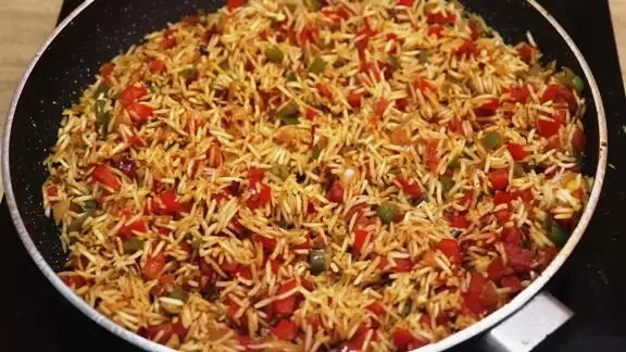 sateting rice with vegetables in the pan.
