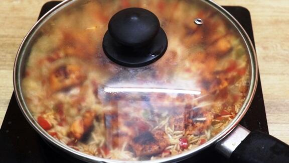 simmering the cajun chicken and rice in a pan.