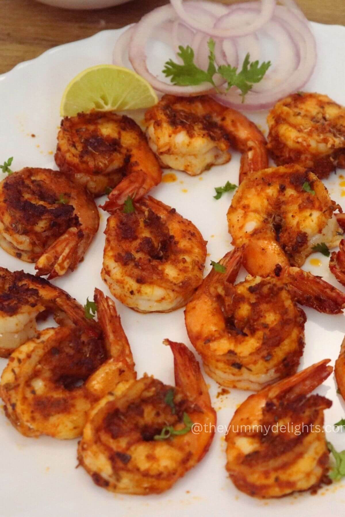 close-up of pan-fried Cajun shrimp served on a white plate.