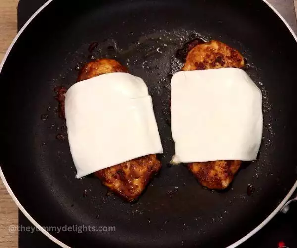 placing the cheese slices over cooked chicken breast.