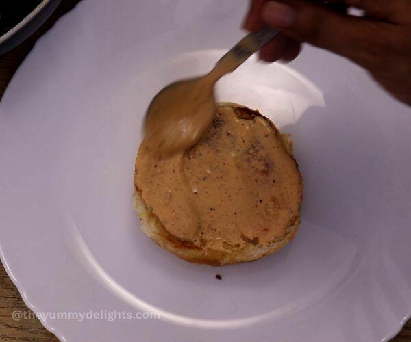 assembling chipotle chicken sandwich. It shows applying chipotle mayo on the toasted buns.