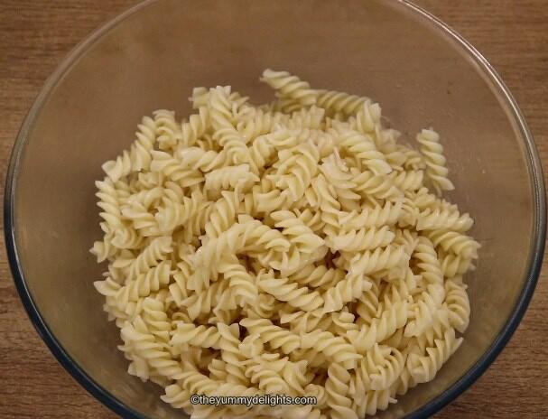 shows image of cooked pasta placed in a mixing bowl to make greek chicken pasta salad.