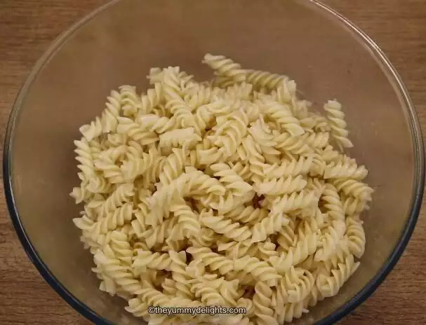 shows image of cooked pasta placed in a mixing bowl to make greek chicken pasta salad.