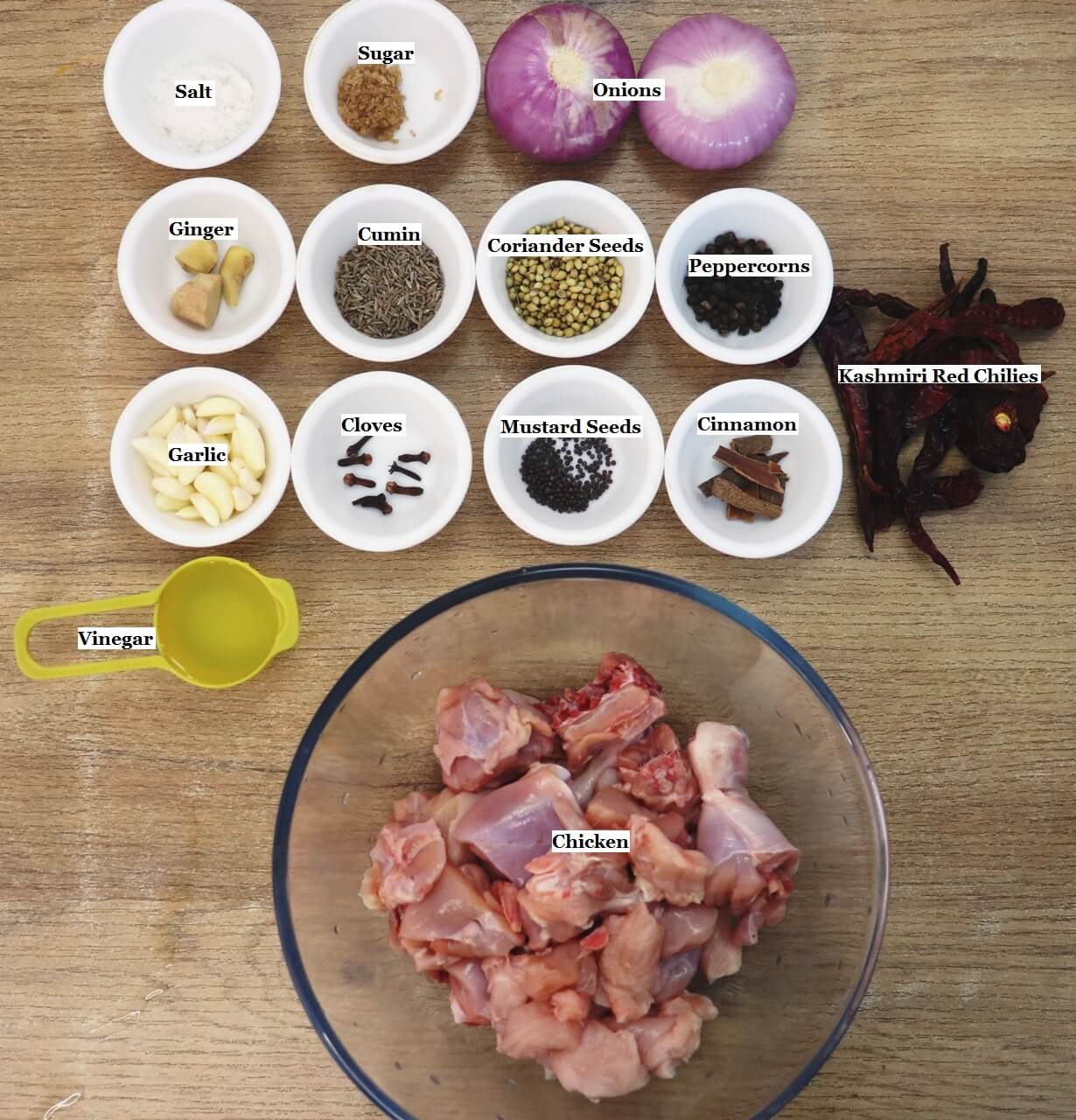 individually labeled ingredients to make chicken vindaloo recipe is laid out on a table.