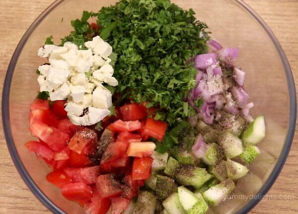 addition of dressing ingredients to mediterranean tomato cucumber salad.