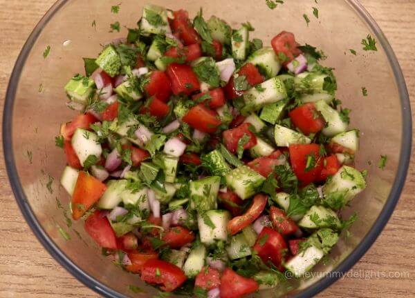 tossing mediterranean tomato cucumber salad.