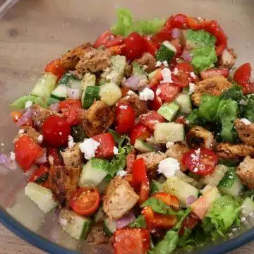 close-up of Mediterranean chicken salad in a glass bowl.