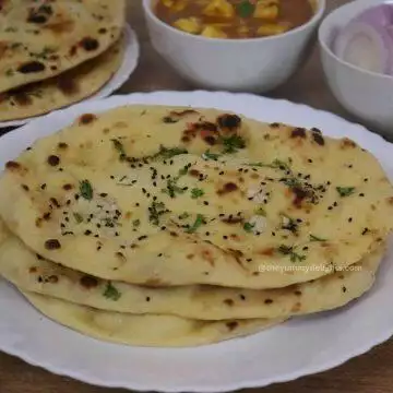 close up of 3 garlic naan bread served on a white plate.