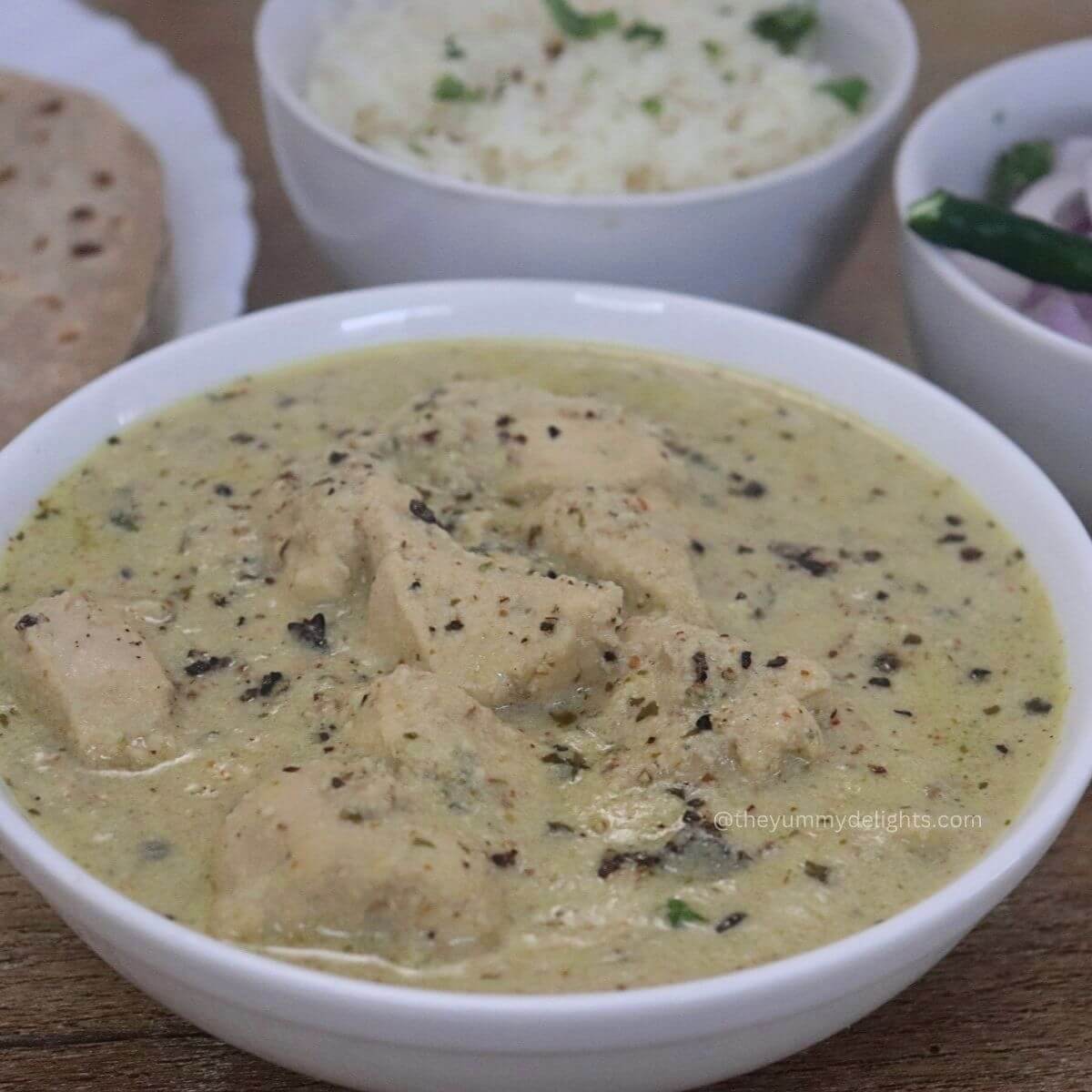 close-up of chicken kali mirch served in a white bowl. Garnished with freshly crushed black pepper.