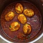 close-up of egg masala in a pot. Garnished with coriander leaves.