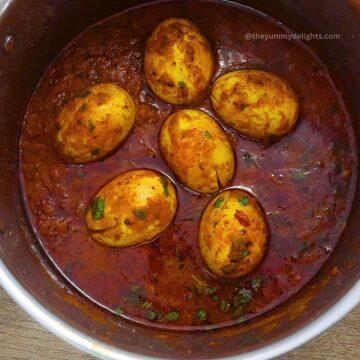 close-up of egg masala in a pot. Garnished with coriander leaves.